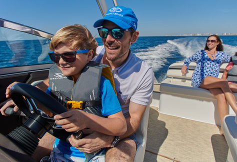 Father and Son Driving a Cobalt Boat with Mother and Daughter Relaxing in Rear of Boat