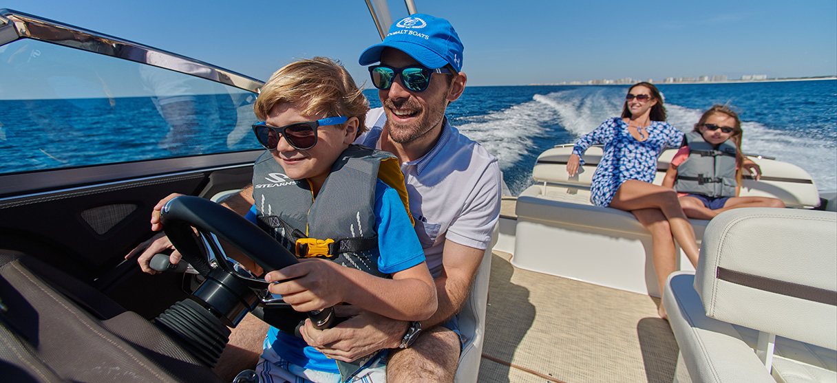 Father and Son Driving a Cobalt Boat with Mother and Daughter Relaxing in Rear of Boat