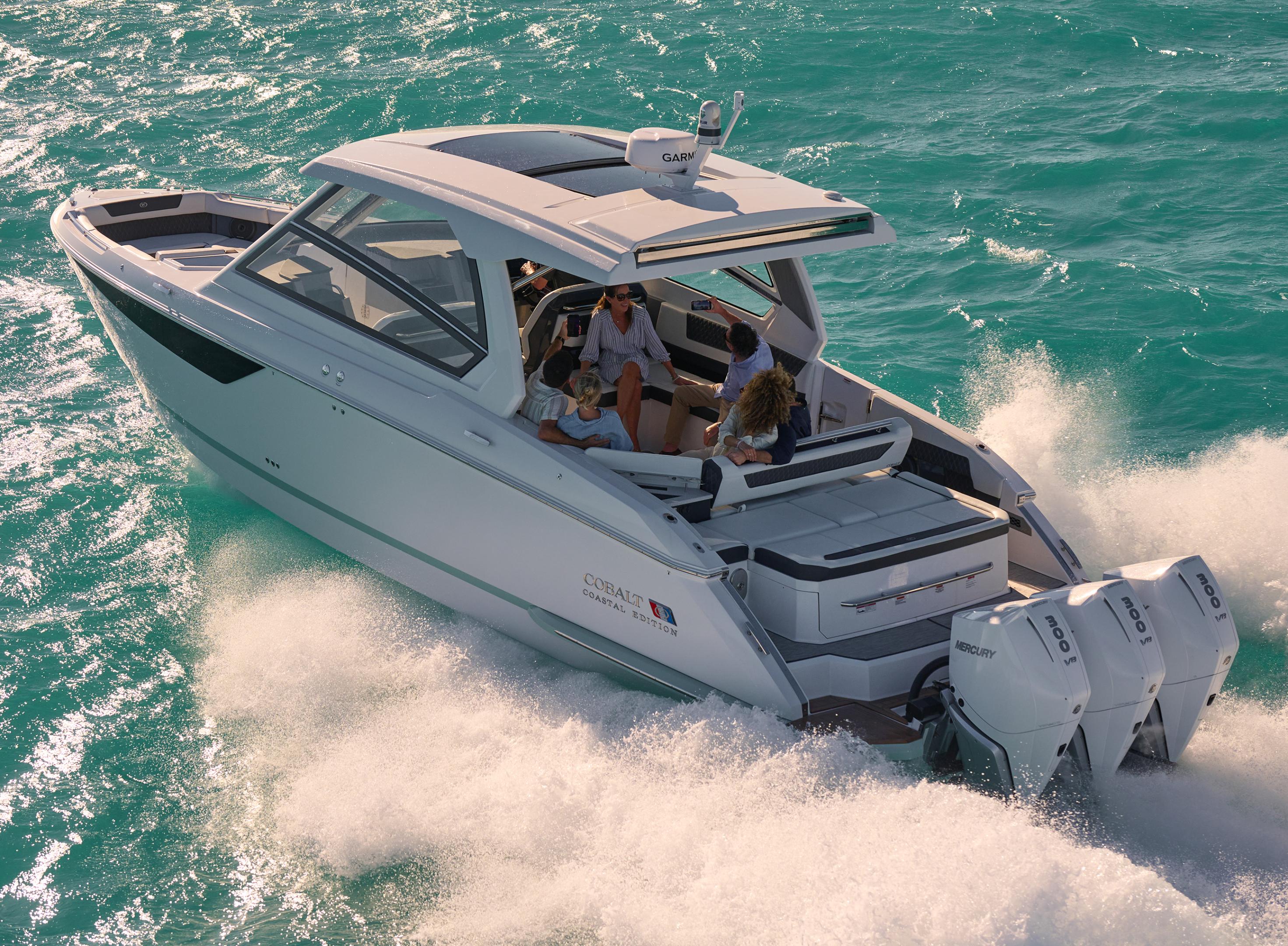 Family relaxing in the aft cockpit of a white Cobalt Coastal Edition boat powered by dual Mercury outboard engines