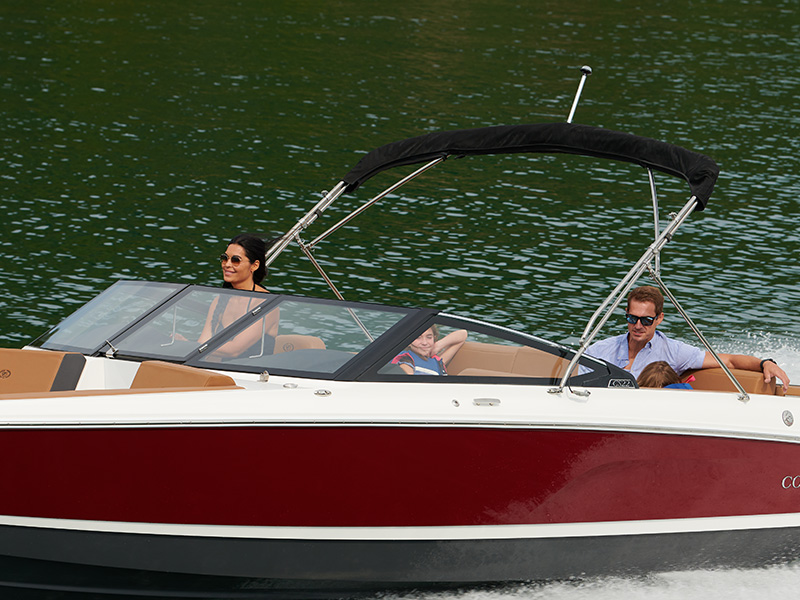 Family on a Cobalt CS22 on turquoise water showing the new Obsidian dark-frame windshield and helm area with passengers aboard