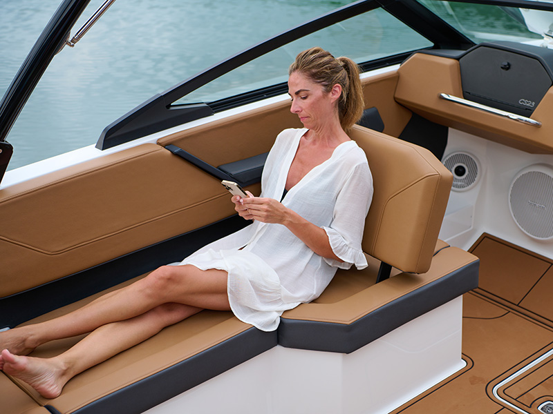 Woman relaxing on the Cobalt CS23 convertible passenger seat with tan leather upholstery and CS23 badge visible on the console