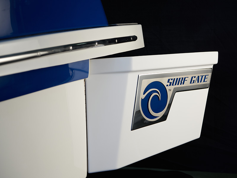 Close-up of the Cobalt CS23 Surf Gate badge with blue wave logo on white and blue hull stern showing branded Surf Gate technology