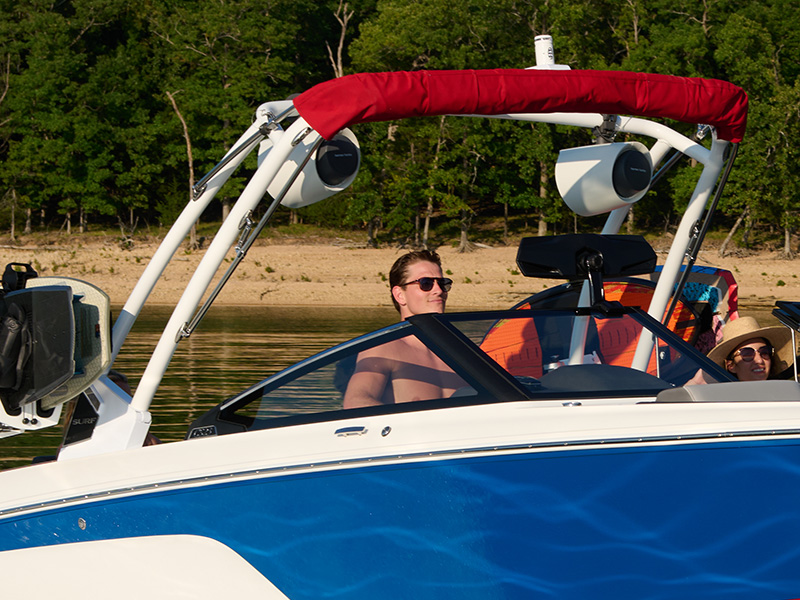 Cobalt CS23 Surf with red bimini and Zenith arch surf tower with tower speakers and crew aboard on a sandy-bottom lakeshore