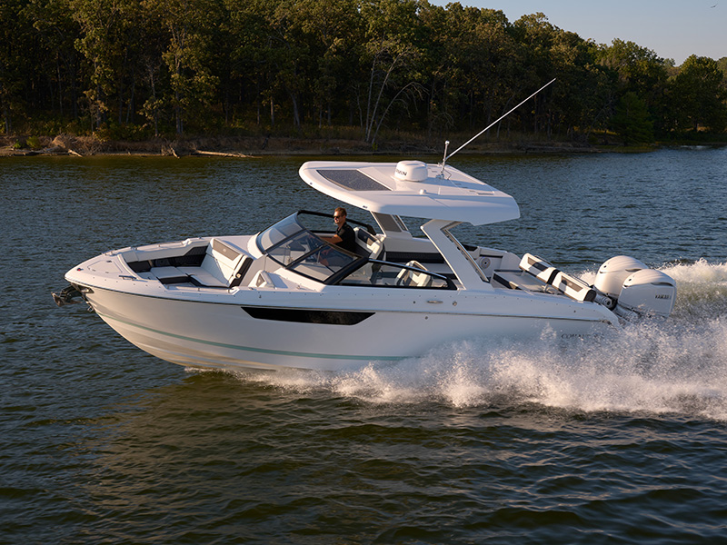 Cobalt R31 Sterndrive running at speed with arch hardtop, single Yamaha outboard, and forested lake backdrop