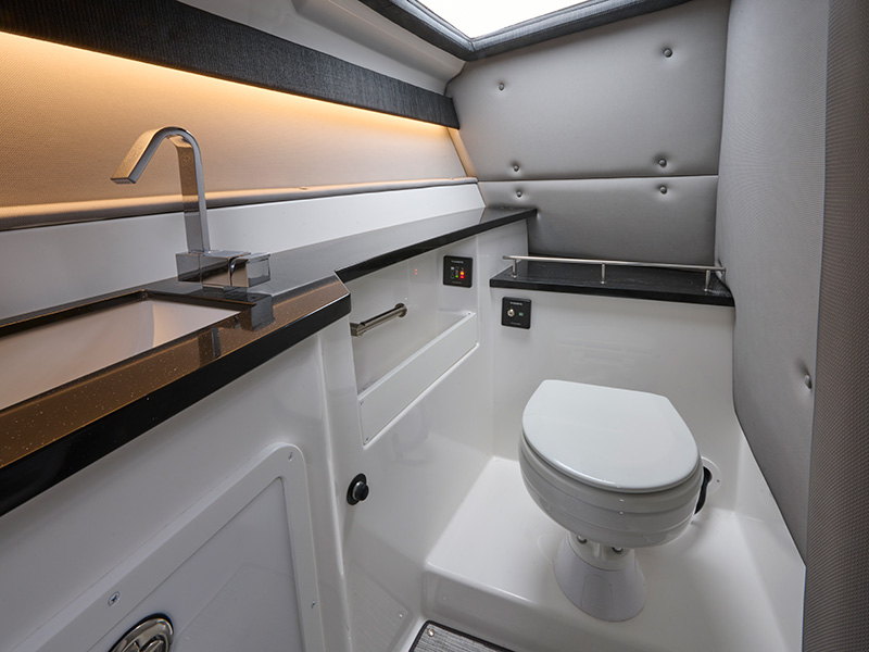 Cobalt R33 Coastal head compartment with marine toilet, granite countertop, LED under-lighting, and tufted upholstered walls