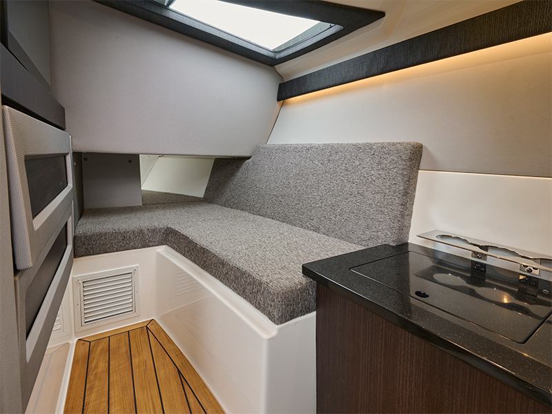 Cobalt R33 Sterndrive interior cabin with plush gray seating, dark wood trim, microwave, and overhead skylight