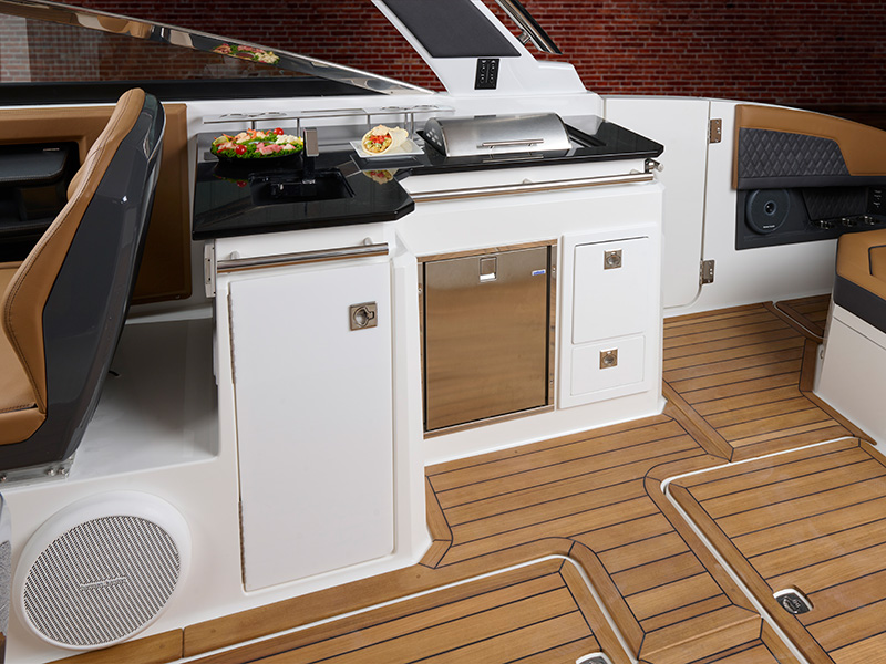 Cobalt R33 Surf gallery console with built-in grill, refrigerator, storage drawers, and food display on teak-style flooring