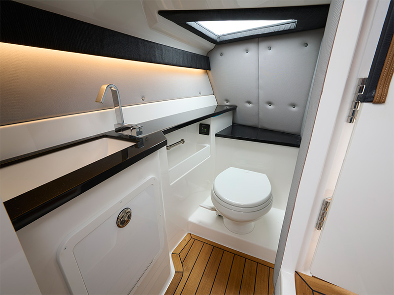 Cobalt R33 Surf head compartment with marine toilet, granite sink counter, LED accent lighting, and tufted upholstered walls