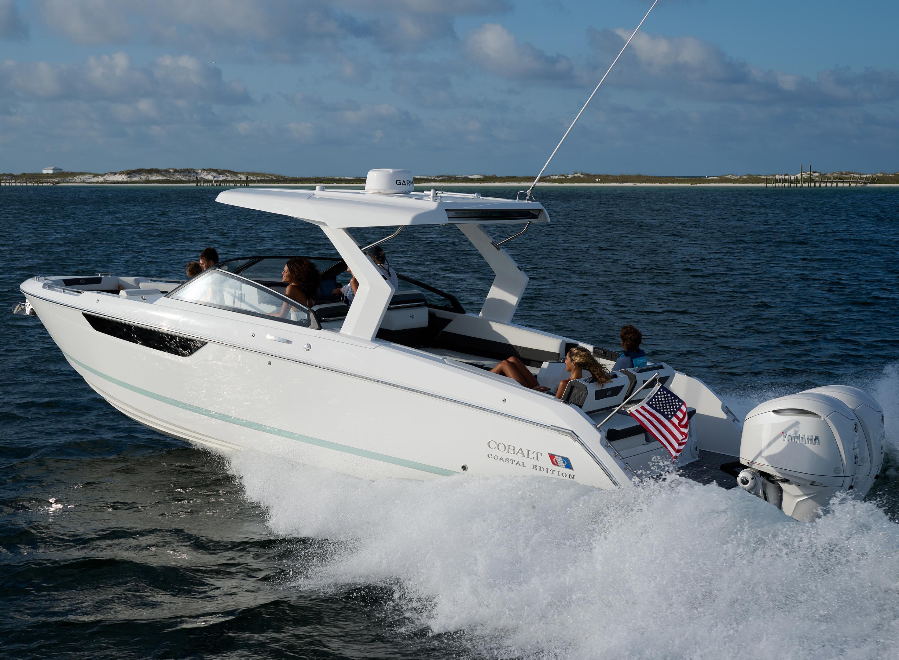 Family cruising aboard a white Cobalt R35 Coastal Coupe with hardtop arch and Yamaha outboard on open ocean water