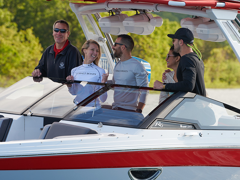 Cobalt R6 Surf black surf windshield with group aboard showing R6 Surf Gate badge and Cobalt Boats branding