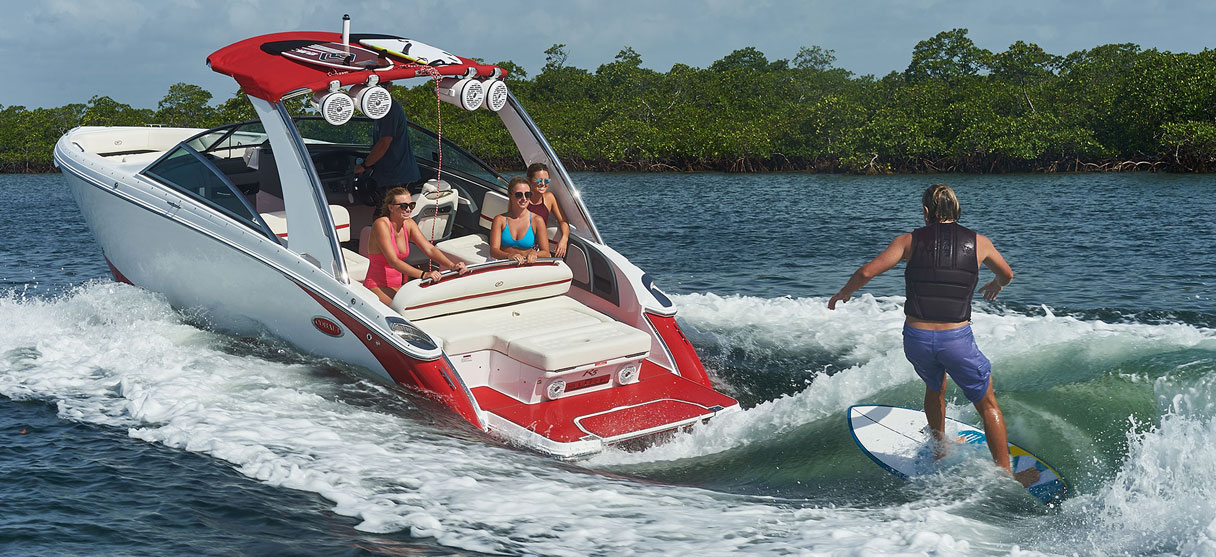 Cobalt Surf Series R5 in White and Knockout Red with Surfer Riding Wave Behind Boat